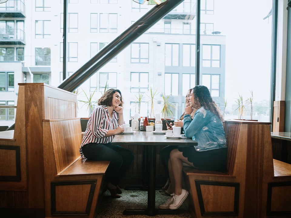 Group of women sit in restaurant booth laughing